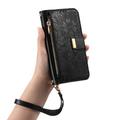 iPhone 16 lommebokveske med blomster- og bladmønster, glidelåslomme og håndleddsstropp - svart